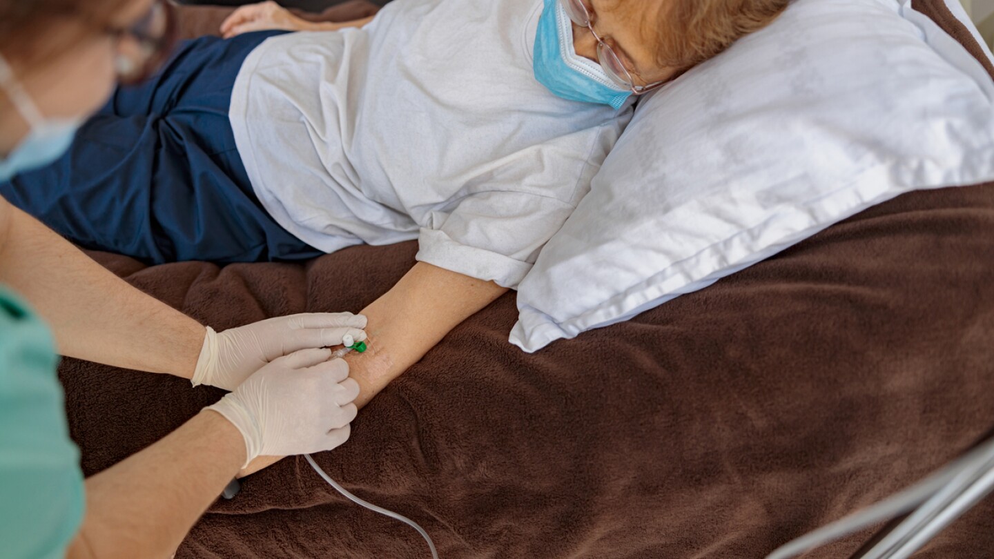Nurse inserts an IV line into a patient with a mask