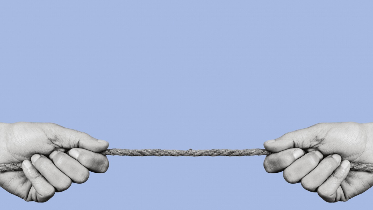 man pulling each of the opposite ends of a rope in black and white, on a blue background with some blank space on top