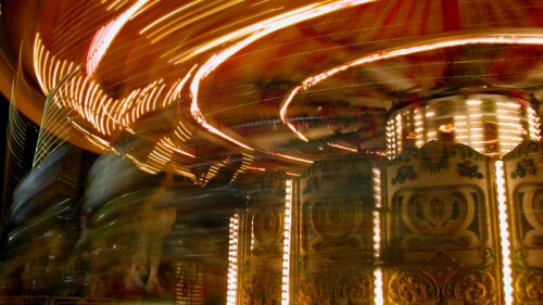 Bright streaks of light of a spinning carousel in motion, capturing the energy and excitement of a night at the fairground