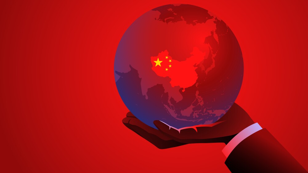 Businessmans hand holding a red globe with the map of China, symbolizing international business, trade, global markets, global influence, economics, or Chinese business ventures