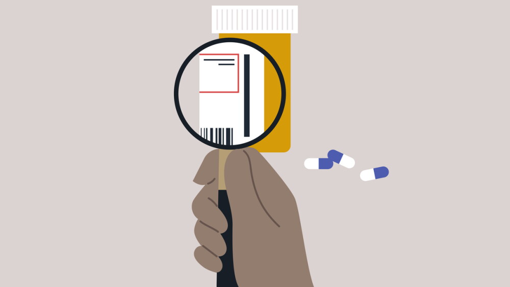 A plastic orange prescription drugs container with white and blue pills, a magnifying glass zooming in on the label