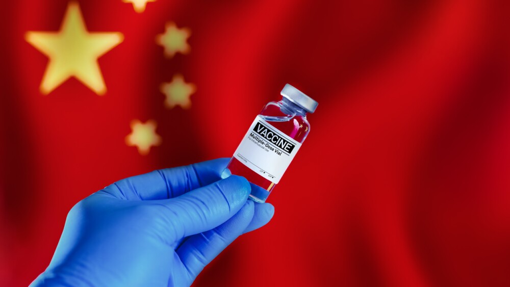 vial of vaccine for the vaccination plan against diseases in the China. Doctor with a vial with doses of the vaccine in front of the China flag