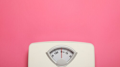 Weigh scales on pink background, top view with space for text. Overweight concept