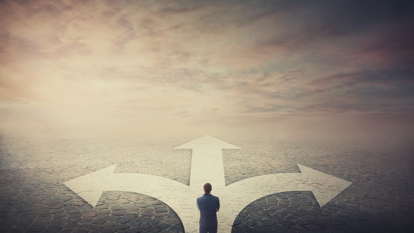 Doubtful businessman stands in front of a crossroad with road split in three different ways as arrows shows opposed courses. Business challenge, choosing a correct pathway. Difficult decision concept