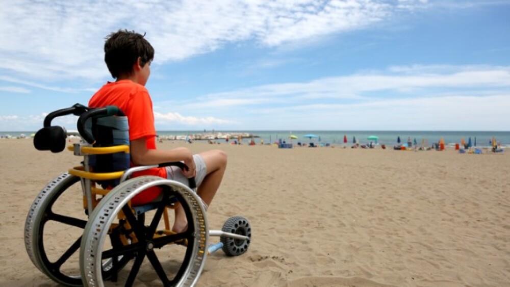 Pictured: Boy in orange shirt on a wheelchair at t