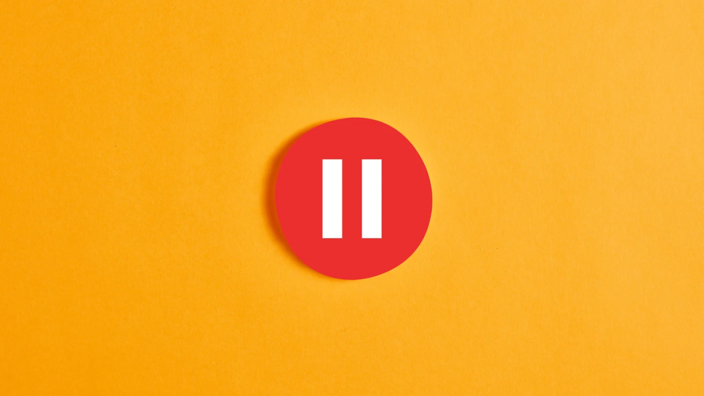 Red round circle with a pause button or icon against yellow background.