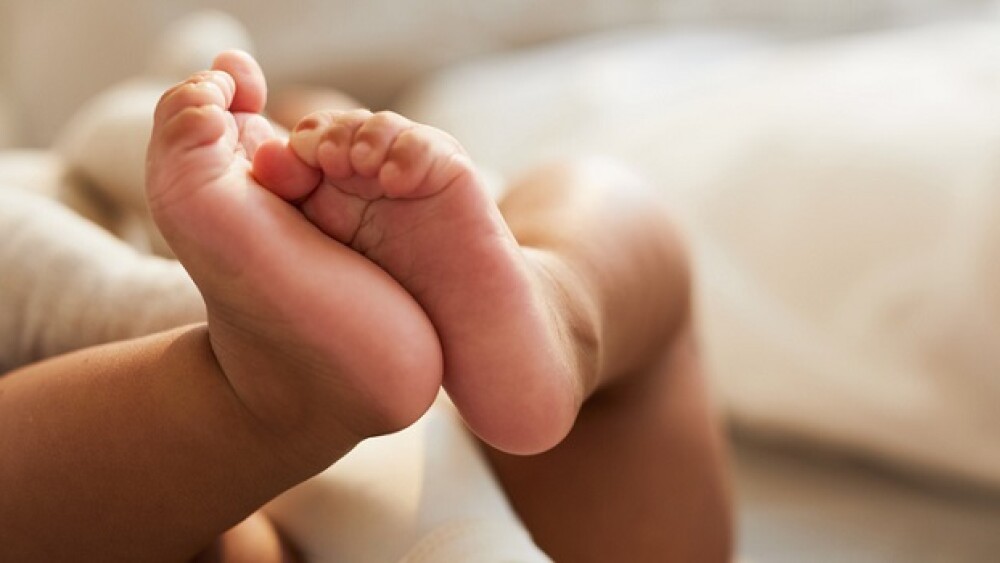 Close-up of unrecognizable cute baby shaking feet while lying in bed, innocence concept