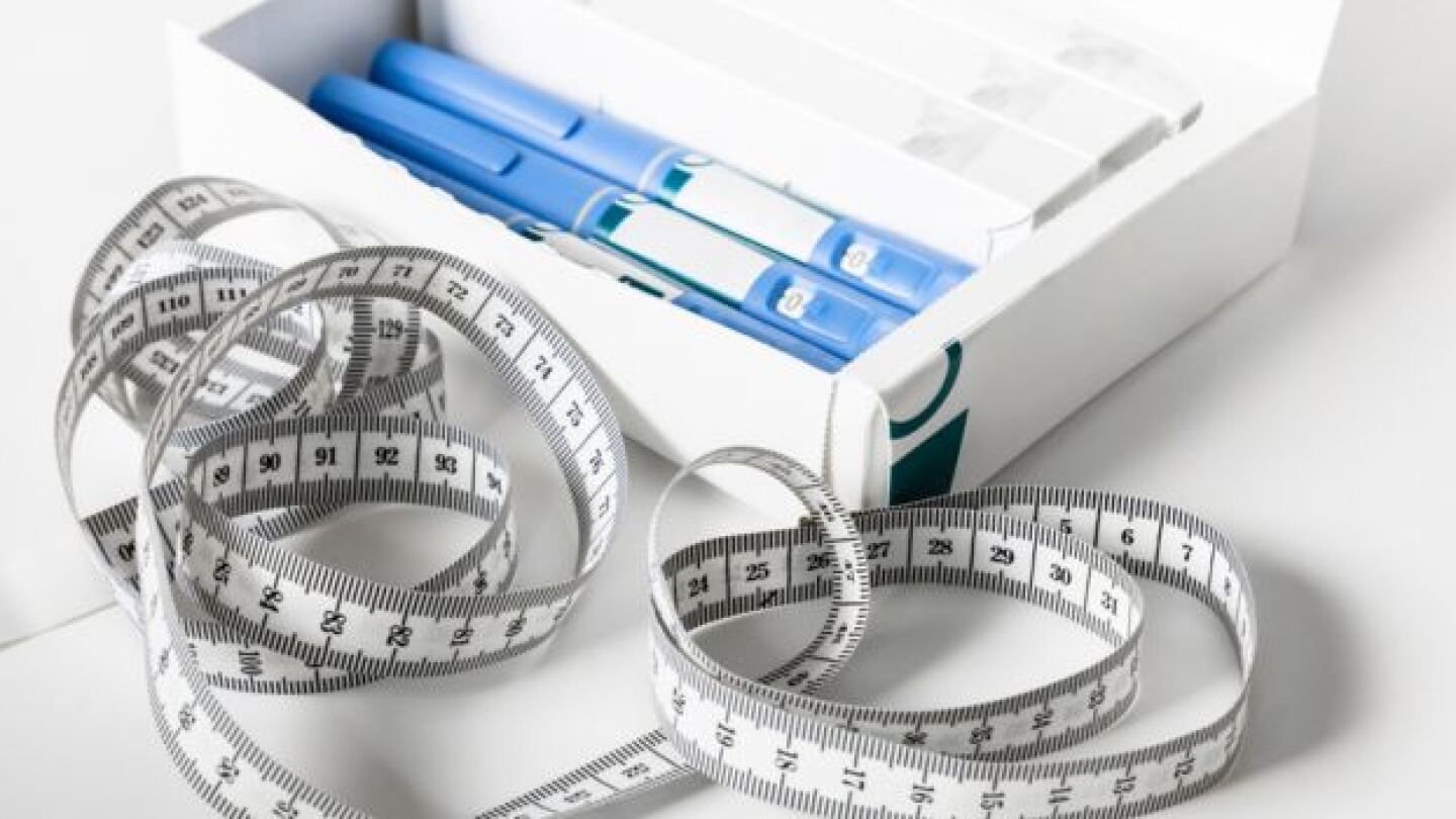 Pictured: Injection pens for GLP-1 medications in a box and a measuring tape
