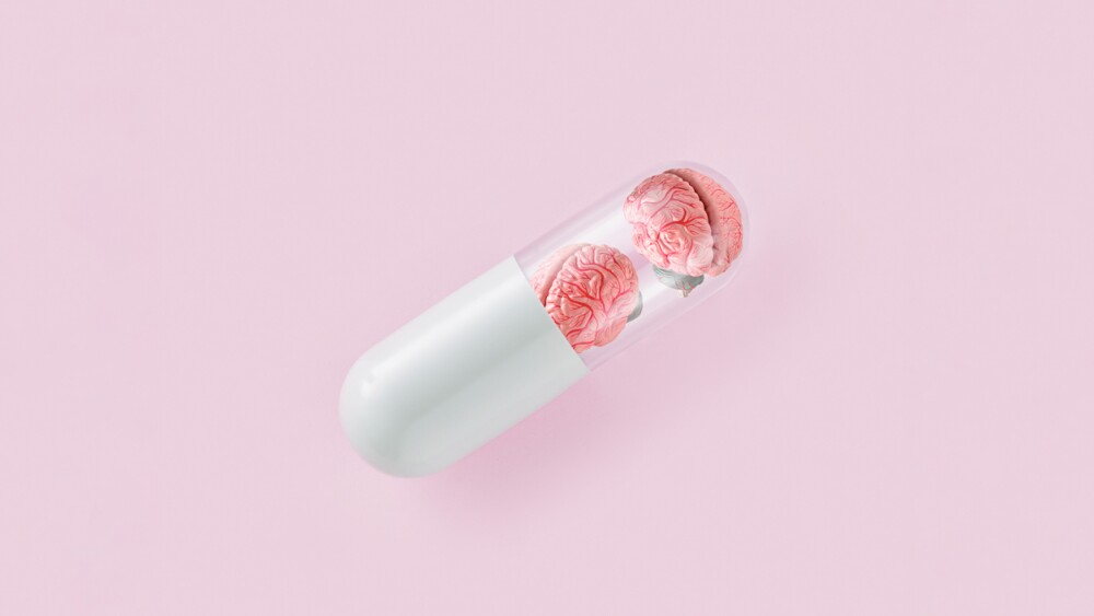 Pill with human brains on isolated pastel pink background. Minimal abstract concept. Lack of wisdom and memory or treatment psychiatric or psychological disorders. Creative idea of mental illness or health care. Flat lay.