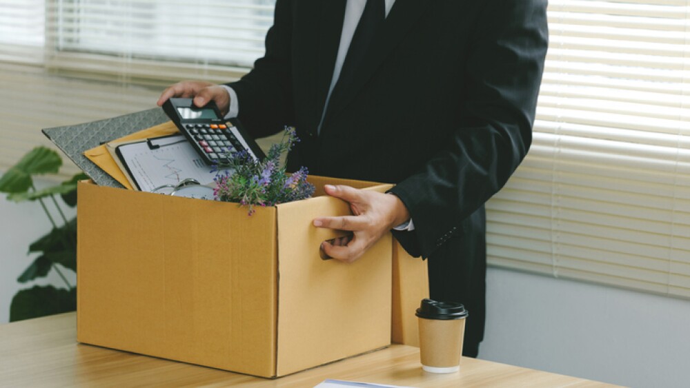 Businessmen grasping cardboard box full of office supplies on a desk in an office