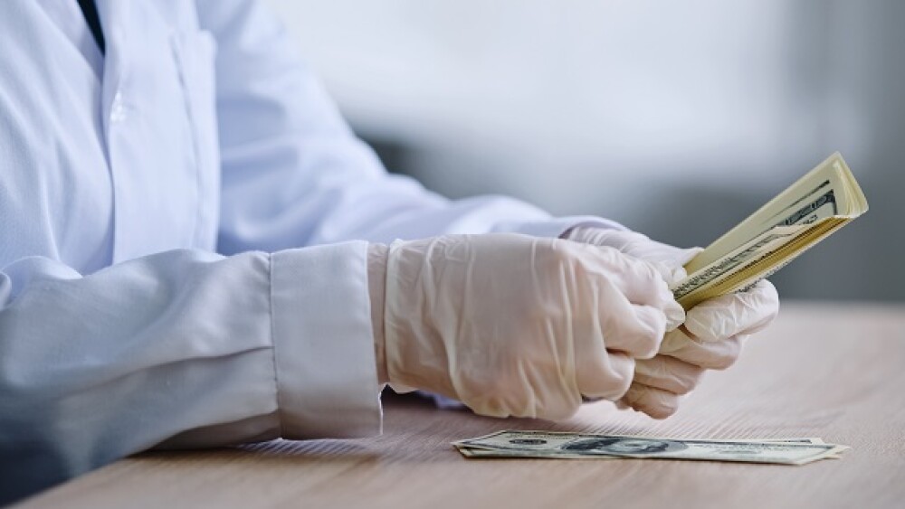Pictured: Scientist counting money/Yuliia/Adobe St