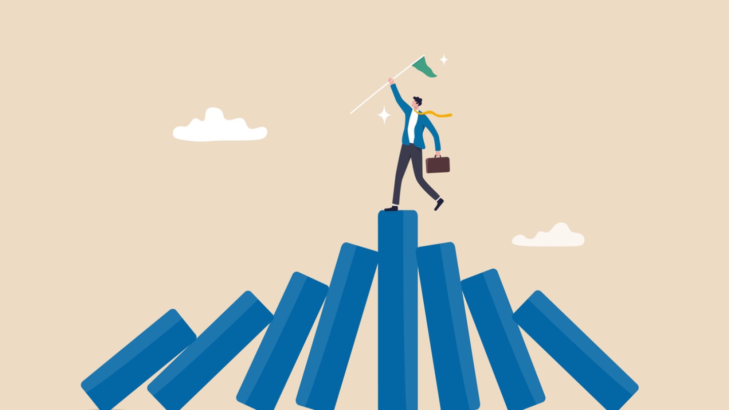 Illustration of businessman with flag looking victorious on top of teetering blocks