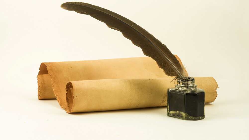 A two old parchment scrolls with a quill in a inkwell on a white background
