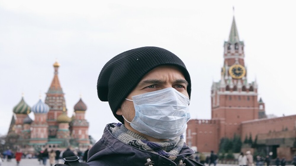 Disease outbreak, coronavirus covid-19 pandemic, air pollution in Moscow, Russia. Portrait of adult man with medical protective mask on face with Kremlin and Red square on background.