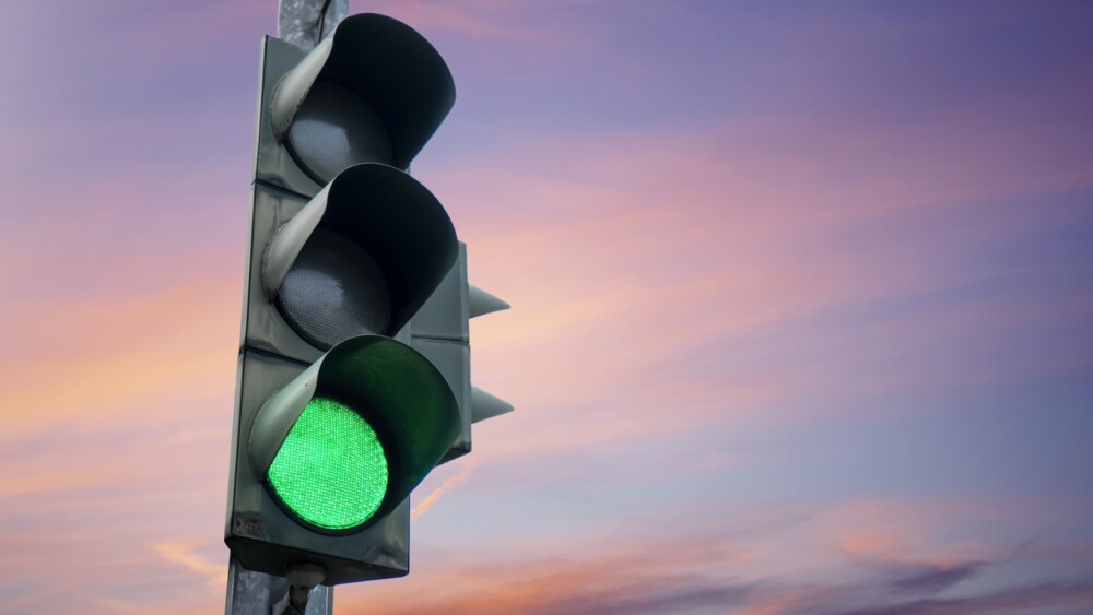 Traffic light in green color, with the dusk sky in the background.