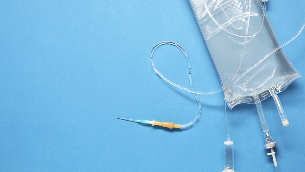 IV infusion set on light blue background, top view. Space for text