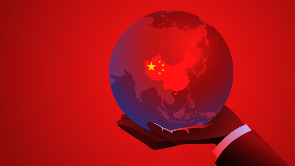 Businessmans hand holding a red globe with the map of China, symbolizing international business, trade, global markets, global influence, economics, or Chinese business ventures