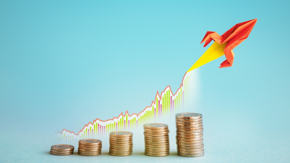 Stacks of coins and a rocket flying above them as a metaphor for income growth.