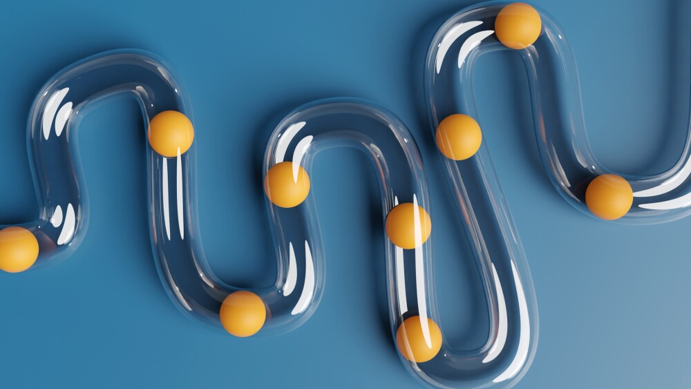 ransparent plastic tube being blocked by orange balls on blue background. Illustration of the concept of digestive disorders and difficulties on career paths
