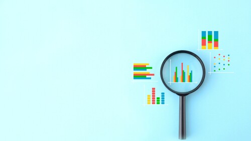 Magnifying glass and various business graphs on light blue background