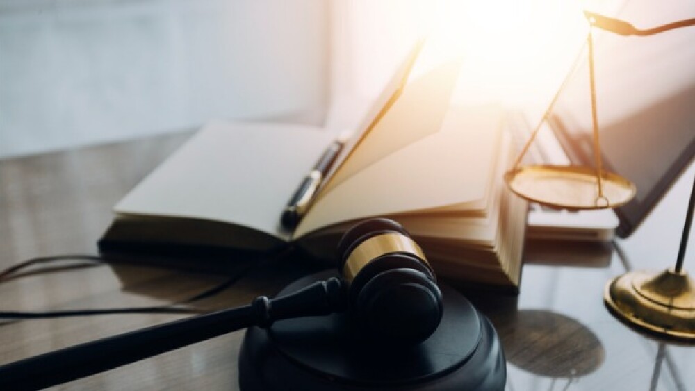 Pictured: Law books and scales of justice on desk/