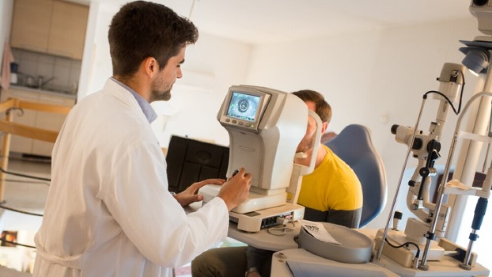 Pictured: Doctor conducts an eye exam on a man/iSt