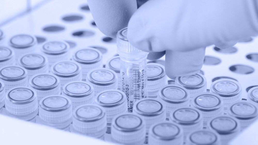 Scientist removes a tube. Gloved hand. Light blue tint applied to image.