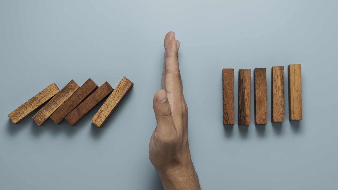 Hands protect to stop rectangle block dominos with others rectangle standing. Risk and crisis management concept.