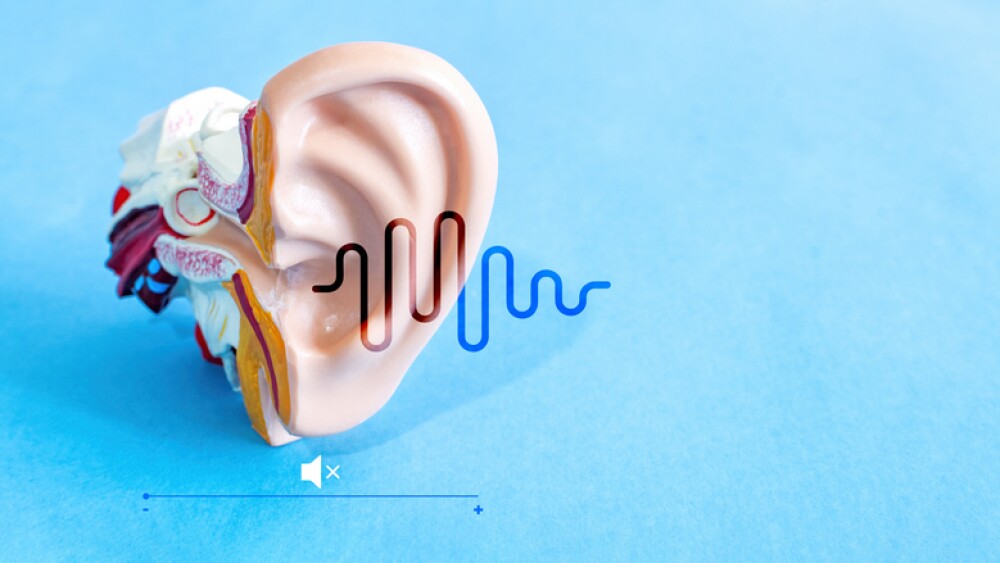 Anatomical model of human ear with luminous sound wave on blue background. Auditory health.