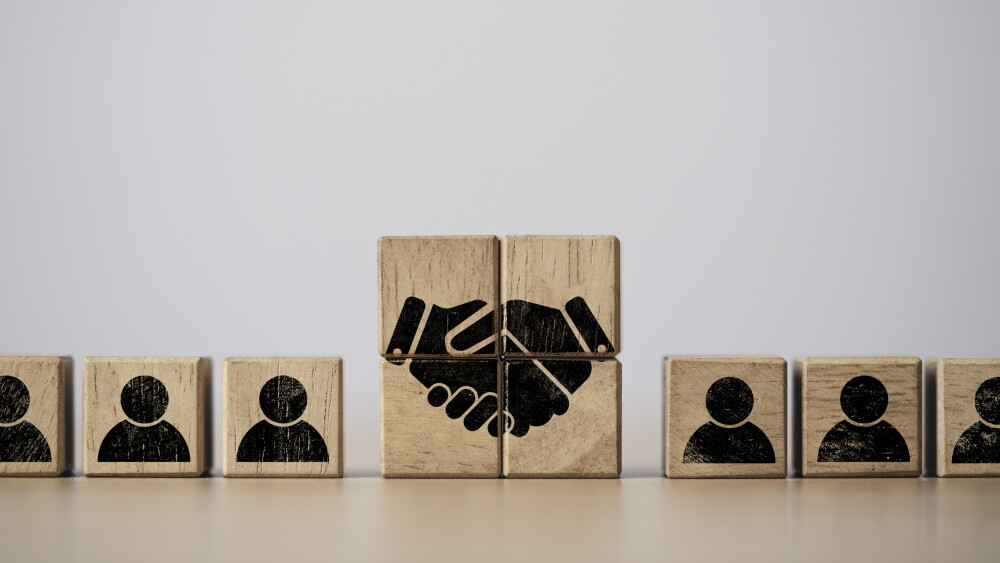 Hand shaking print screen on wooden block cube between human icon for business deal and agreement concept.