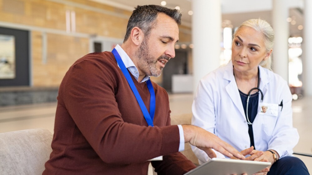 A doctor listens as a representative speaks, using