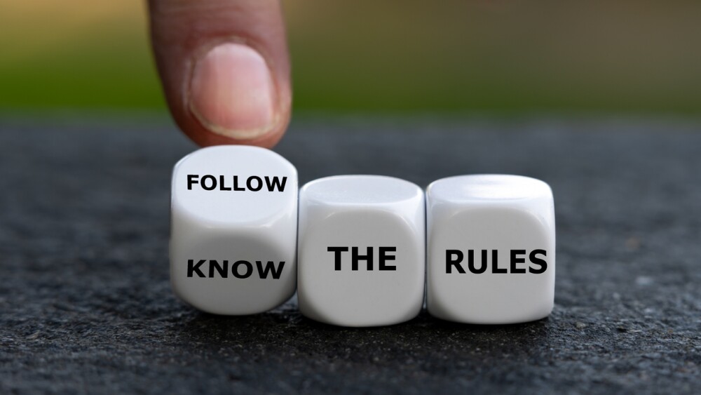 Hand turns dice and changes the expression 'know the rules'. to 'follow the rules'.