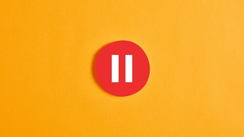 Red round circle with a pause button or icon against yellow background.