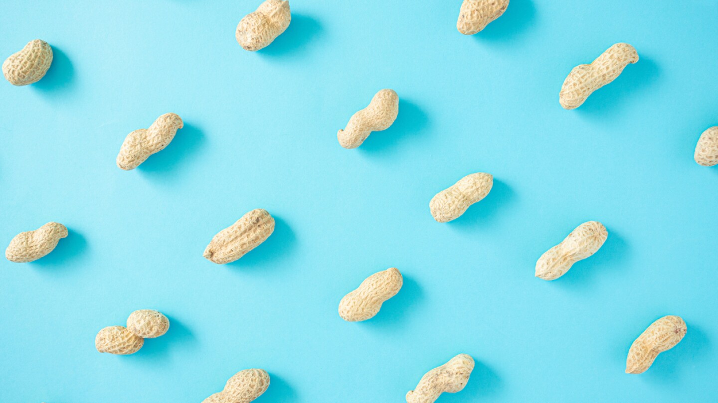 Beautiful colorful unpeeled peanut pattern on a light blue background. Flat lay arrangement, top view.