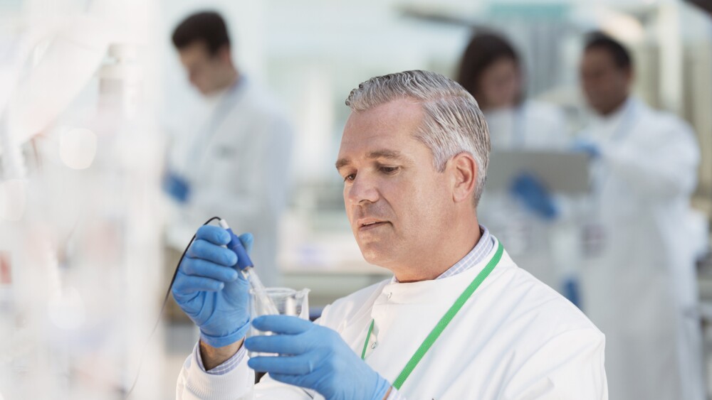 Quality control professional examines sample in beaker in laboratory