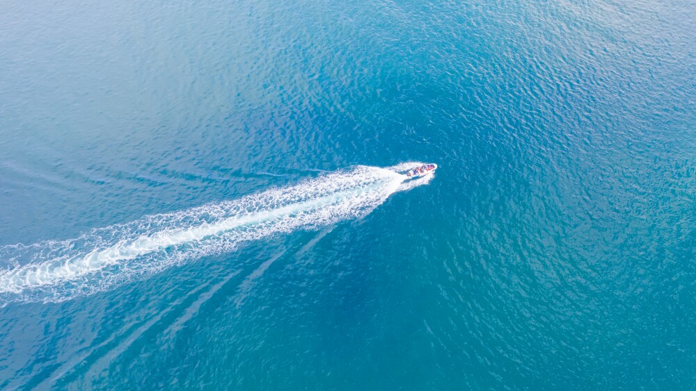 Top view of a white boat with a train sailing to the blue sea