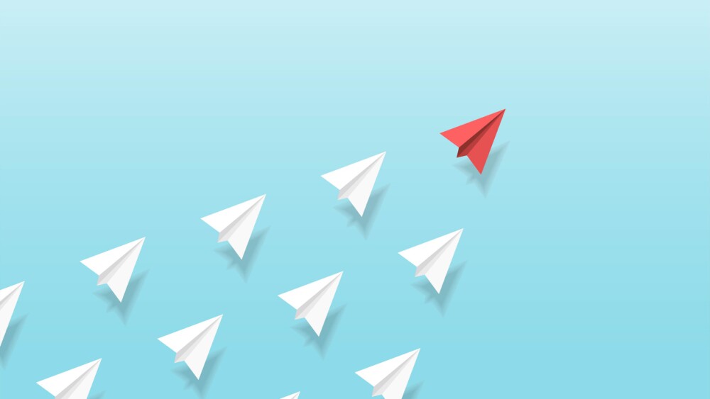 Illustration of red paper plane leading white paper planes up into the sky