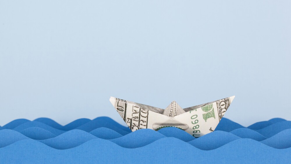 Dollar boat swimming on paper waves