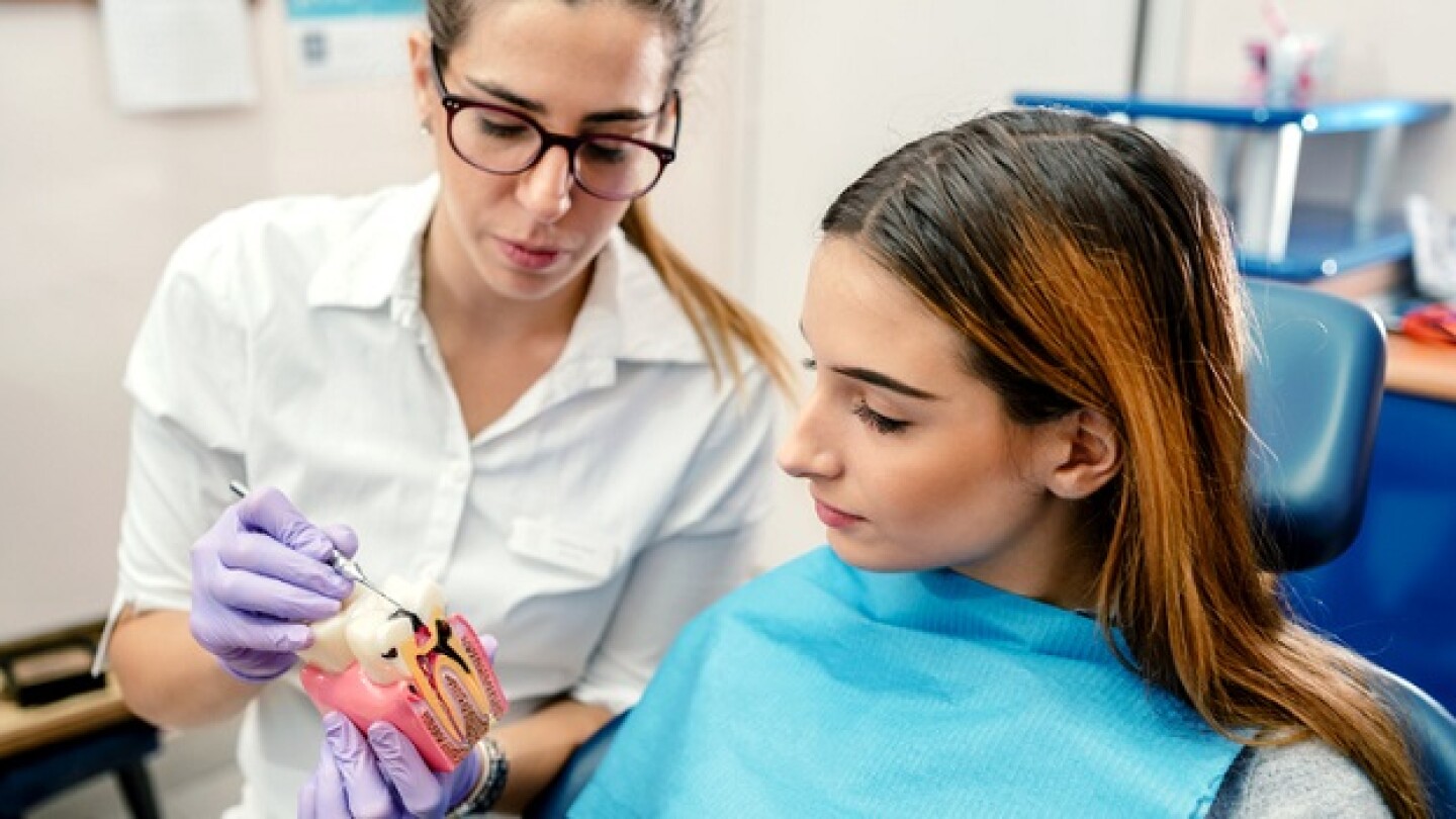 Dentist explaining what dental cavity looks to a patient sitting on a dentist's chair