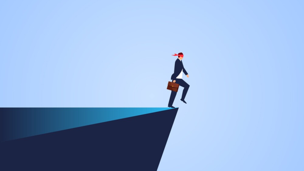 Blindness and crisis, blindfolded businessman walks to the cliff