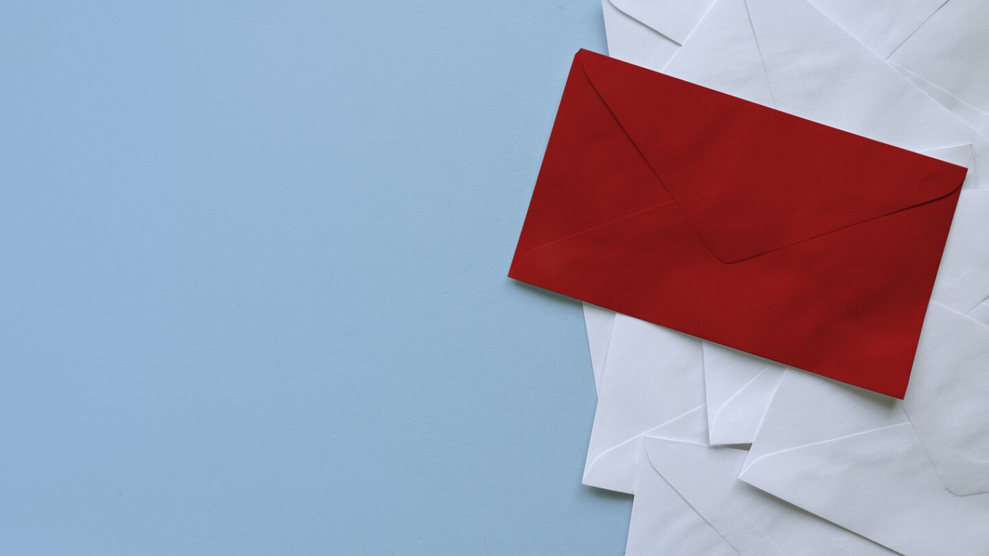 A stack of white envelopes with a red envelope on top. Blue background with copy space.
