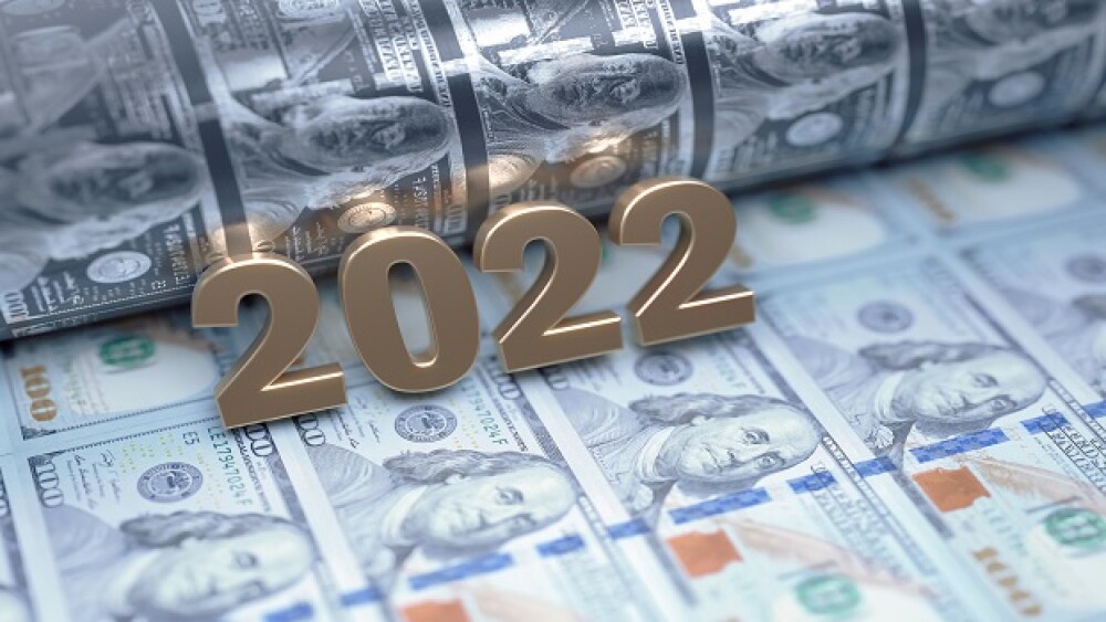 Gold colored 2022 sitting over American Dollar bills. Selective focus. Horizontal composition with copy space. Money printing and inflation concept.