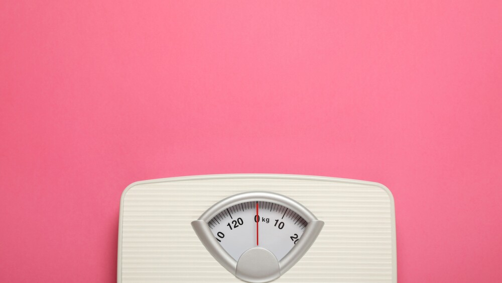 Weigh scales on pink background, top view with space for text. Overweight concept