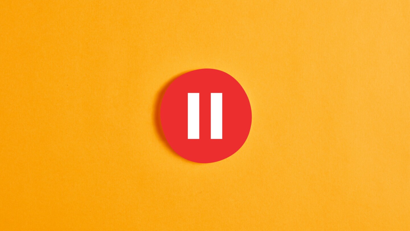 Red round circle with a pause button or icon against yellow background.