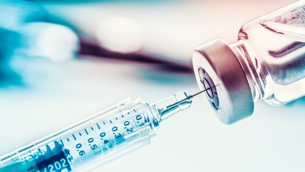 Pictured: Syringe pulling vaccine from a vial / Ad
