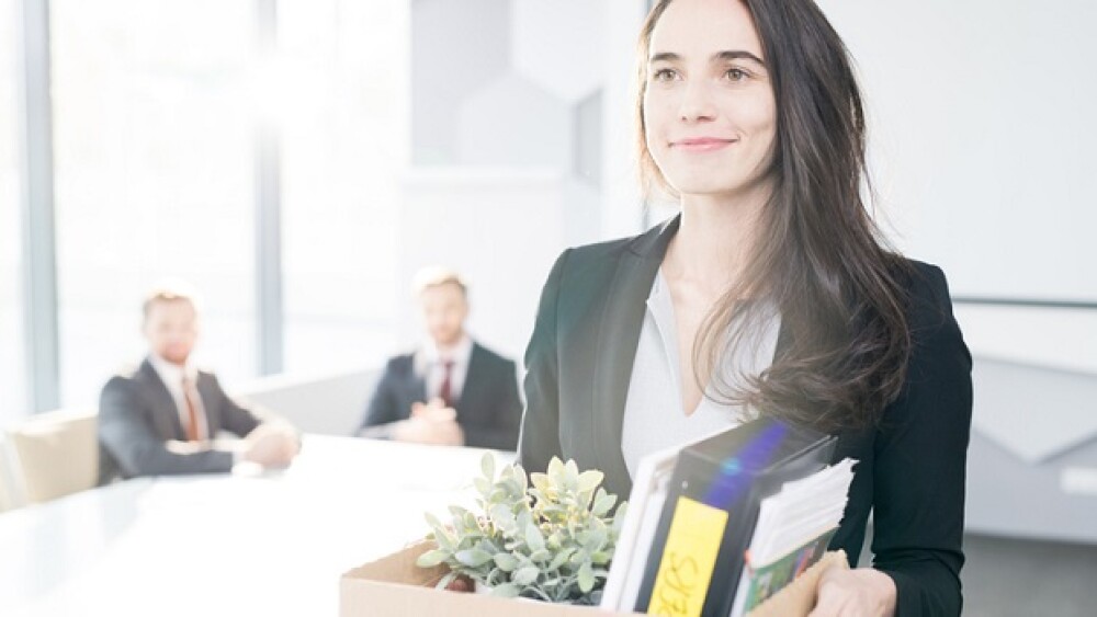 Waist up portrait of smiling young businesswoman holding box of personal belongings leaving office after quitting job, copy space