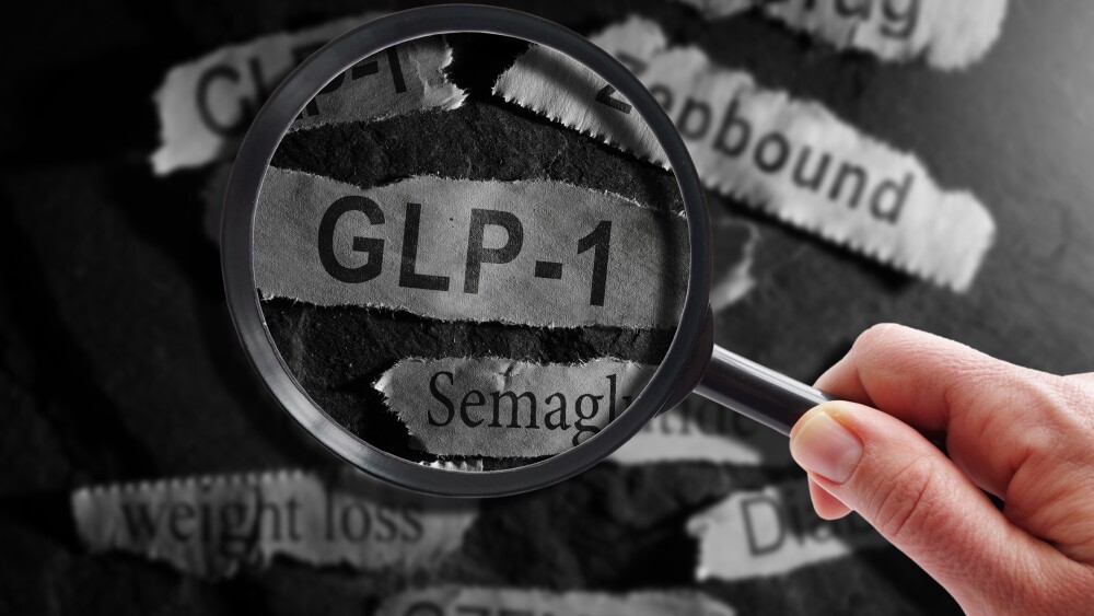 Raleigh, NC - USA - 06-13-2024: GLP-1 related drugs newspaper headlines with hand and magnifying glass