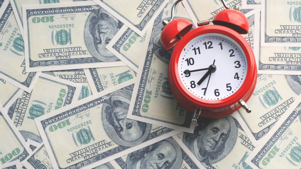Red alarm clock on dollar banknotes. Retro style alarm clock and dollars. Time to work / tome to make money concept.