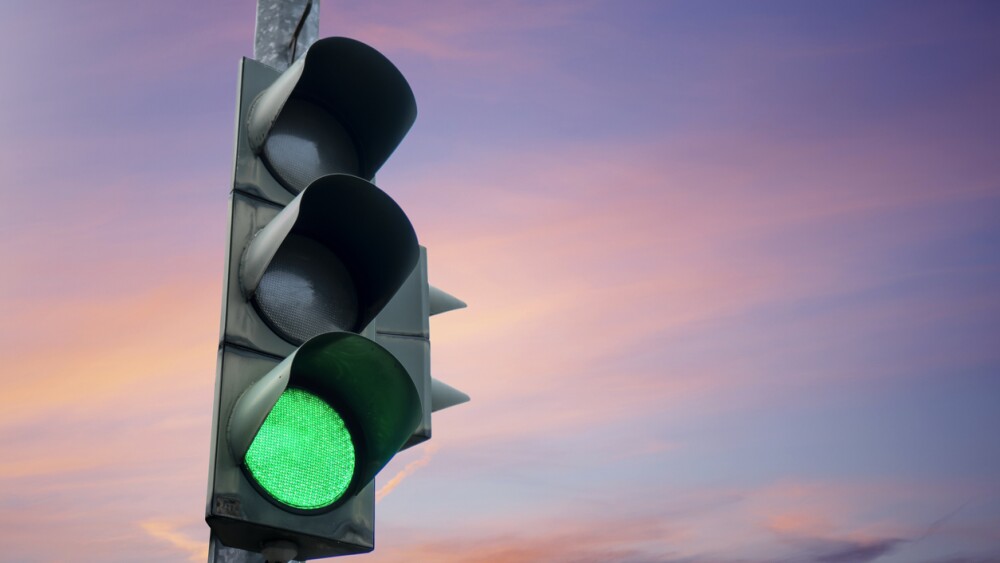 Traffic light in green color, with the dusk sky in the background.