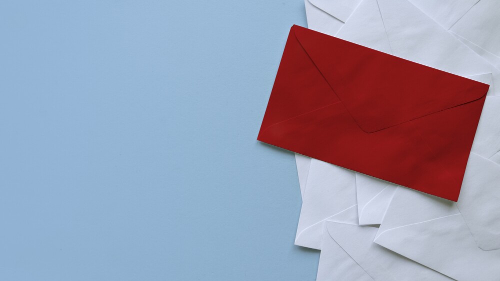 A stack of white envelopes with a red envelope on top. Blue background with copy space.